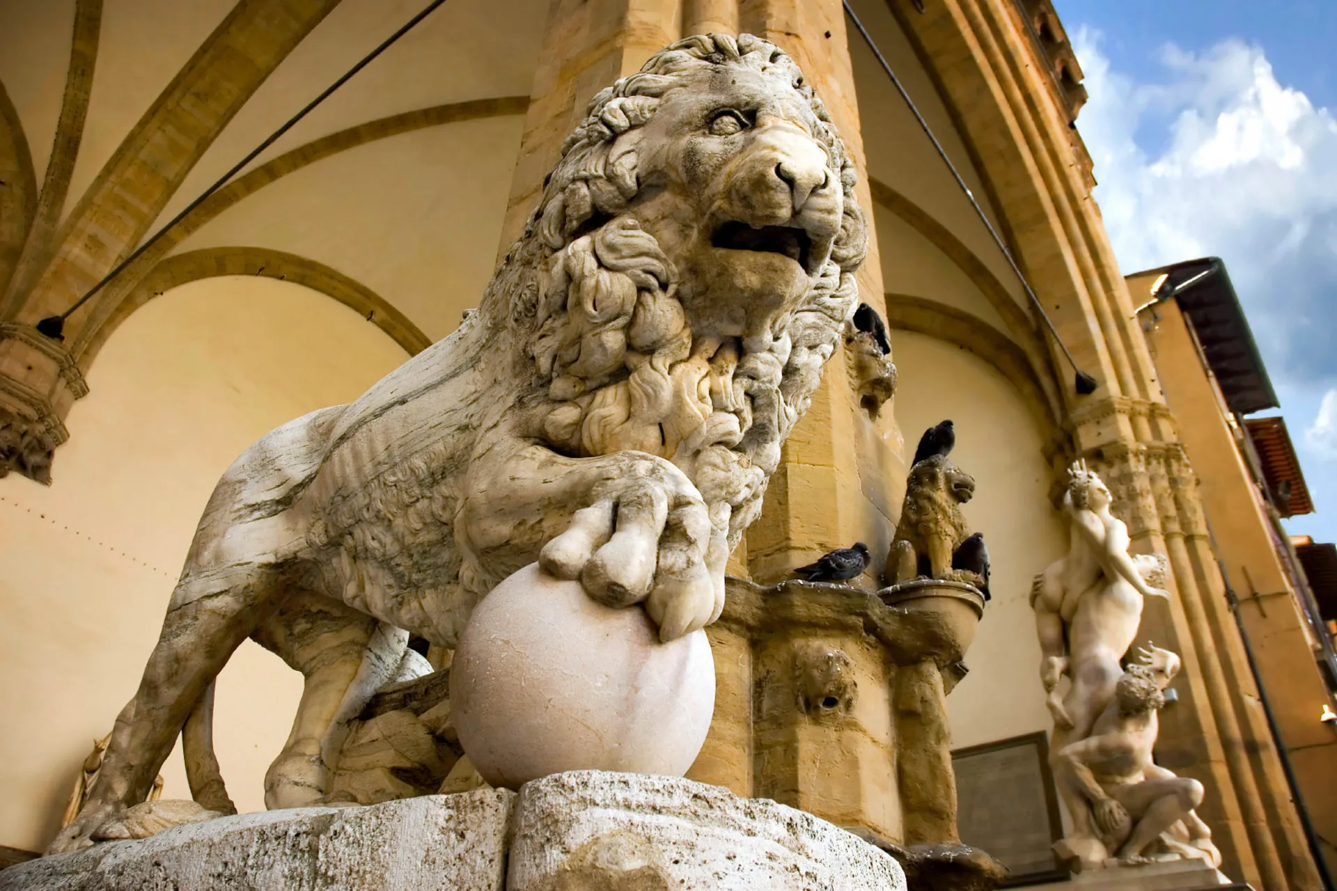 Løveskulptur i marmor omgitt av kunstneriske detaljer