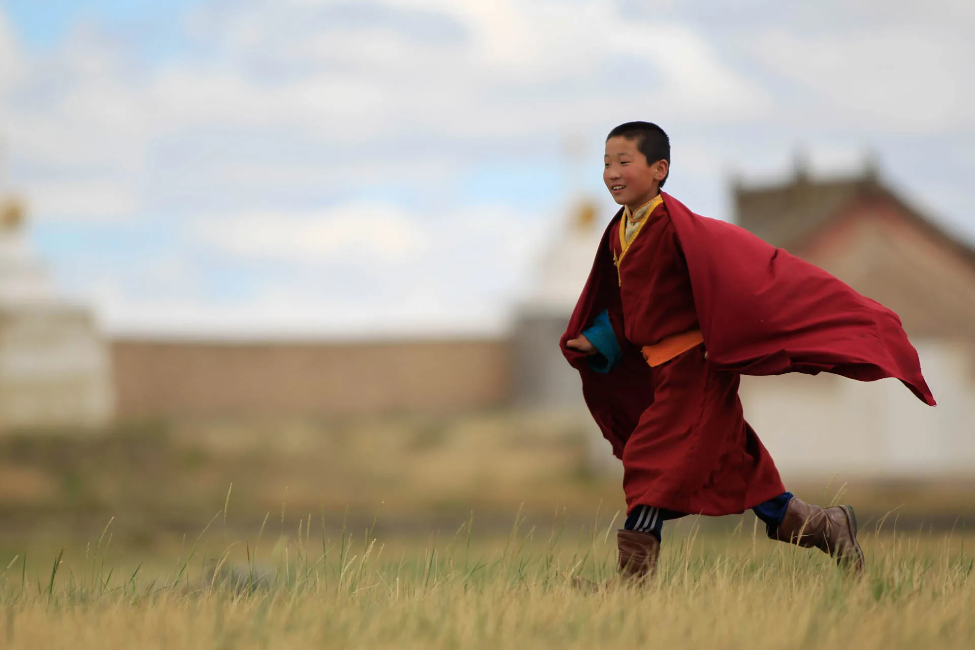 Ung buddhistmunk i Mongolia iført tradisjonell rød munkekåpe Ung buddhistmunk i Mongolia iført tradisjonell rød munkekåpe