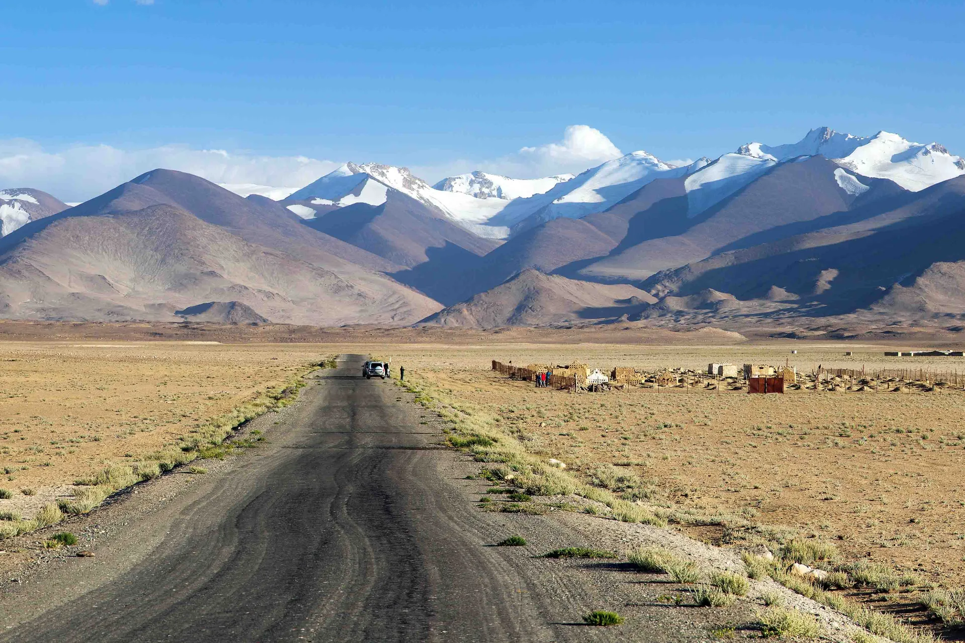 En øde og barsk strekning langs den berømte Pamir Highway med Tadsjikistans snødekte fjelltopper i bakgrunnen