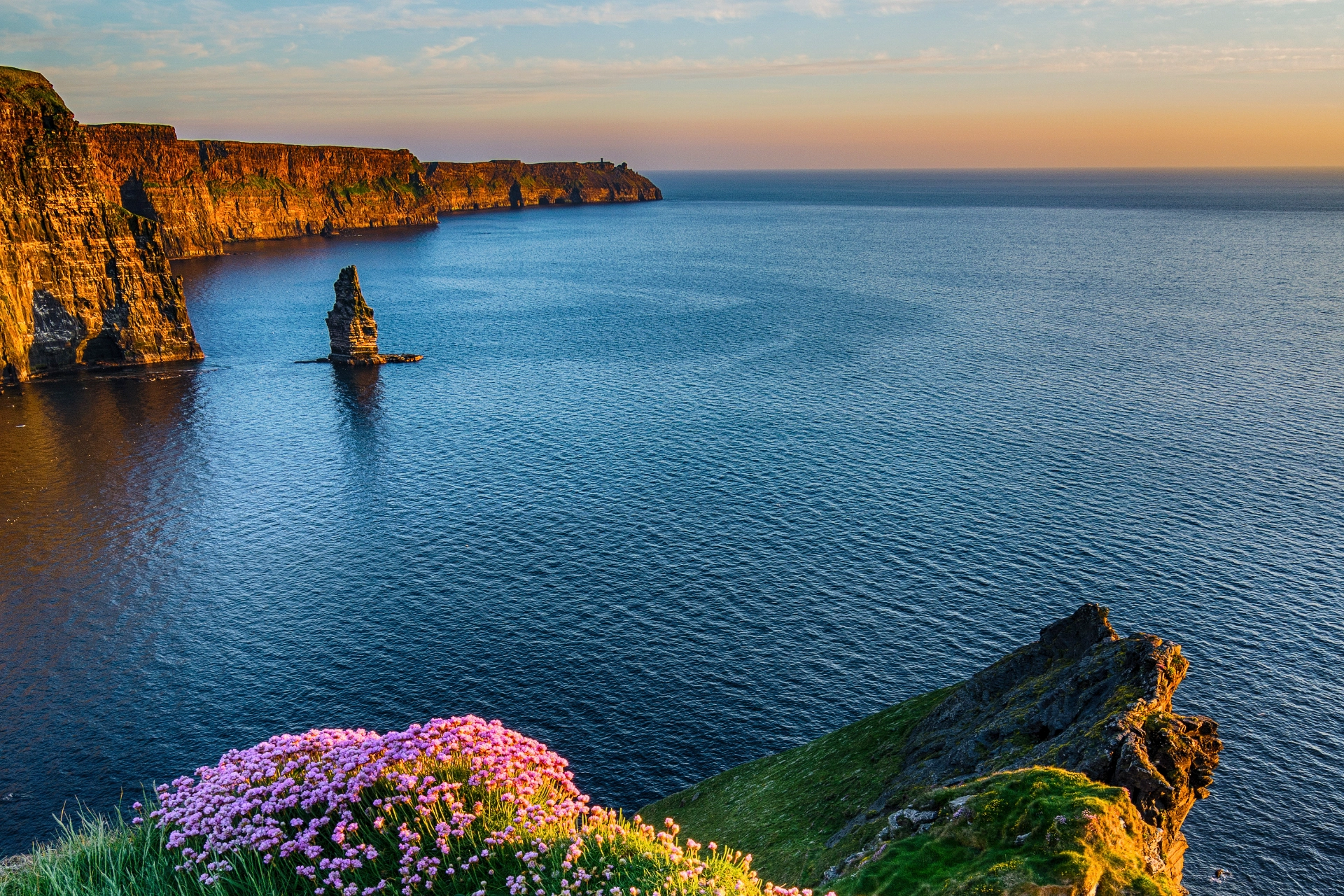 Cliffs of Moher i gyllent kveldslys. Klippesøylen i vannet heter Branaunmore