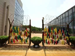 DMZ – fargerike bånd hengt på gjerdet symboliserer ønsker om fred og gjenforening mellom Nord- og Sør-Korea DMZ – fargerike bånd hengt på gjerdet symboliserer ønsker om fred og gjenforening mellom Nord- og Sør-Korea