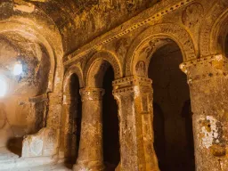 Interiør av en gammel hulekirke i Kappadokia, med utskårne søyler, buer og rester av dekorasjoner i fjellveggene Interiør av en gammel hulekirke i Kappadokia, med utskårne søyler, buer og rester av dekorasjoner i fjellveggene