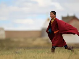 Ung buddhistmunk i Mongolia iført tradisjonell rød munkekåpe Ung buddhistmunk i Mongolia iført tradisjonell rød munkekåpe