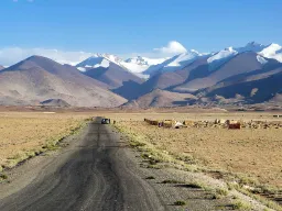 En øde og barsk strekning langs den berømte Pamir Highway med Tadsjikistans snødekte fjelltopper i bakgrunnen