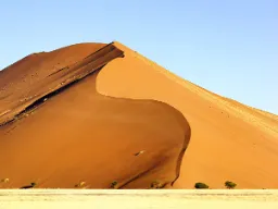 En av Sossusvleis ikoniske røde sanddyner reiser seg majestetisk mot himmelen