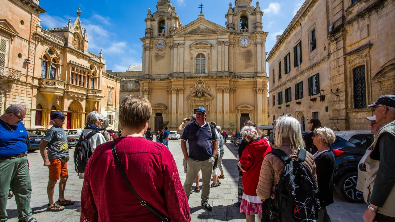 Guiden på jobb i Mdina, Maltas gamle hovedstad, foran den imponerende St. Pauls katedral