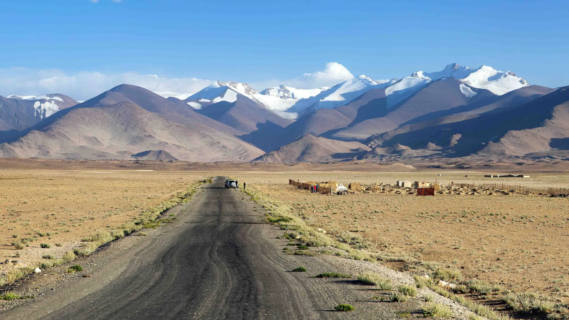 En øde og barsk strekning langs den berømte Pamir Highway med Tadsjikistans snødekte fjelltopper i bakgrunnen